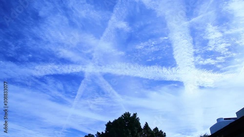 Panning across a heavily sprayed chemtrail sky as the chemicals spread out to cover the blue and reflect the sun away from earth in an effort to reduce global warming. Different stages of spreading.