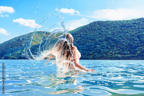 Beautiful girl splashing in the water. Retreat. Vacation. Colorful blue landscape. Rest, relax in nature. Enjoy life. Lifestyle. A young woman swimming in the sea. Color of the year 2020. Tropical.