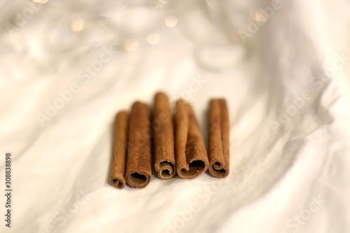 Cinnamon sticks on white background with bokeg lights. Selective focus.  photo