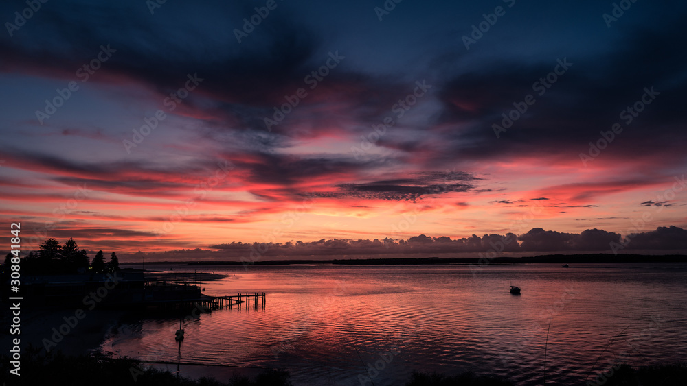 Obraz premium Colourful clouds at dawn over a bay
