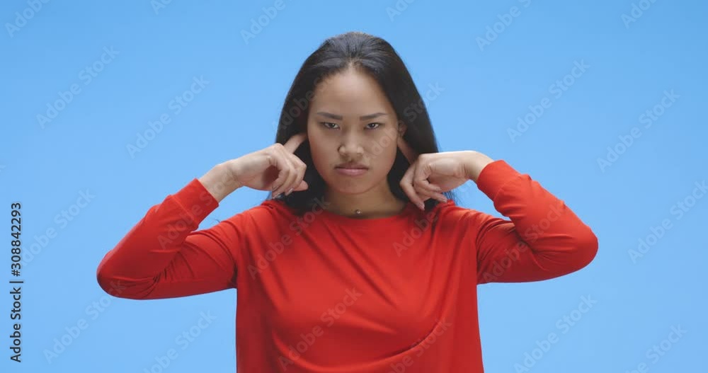 Young woman plugging hear ears with fingers