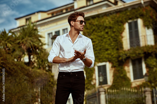 Handsome young man in sunglasses in front of luxury home villa