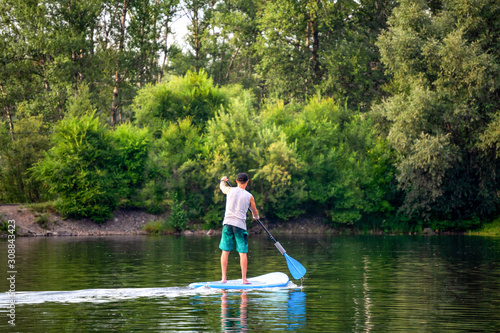 Photography Manl sup surfing paddling on boat on lake river on sunny day.