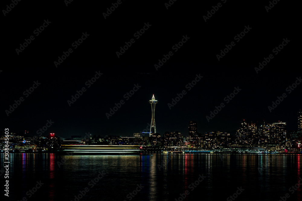 Long exposure ferry crossing Elliott Bay of Seattle with Space needle at night.