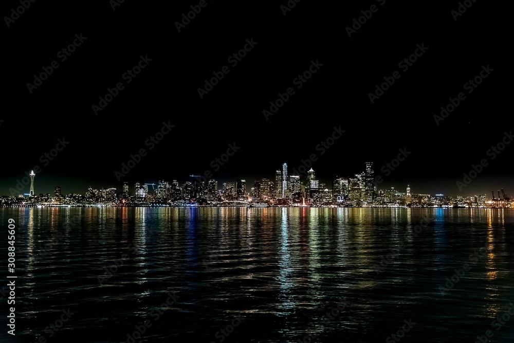 Elliott Bay with Seattle skyline reflecting on waves at night.