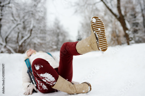 Shot of person during falling in snowy winter park. Woman slip on the icy path, fell and lies.