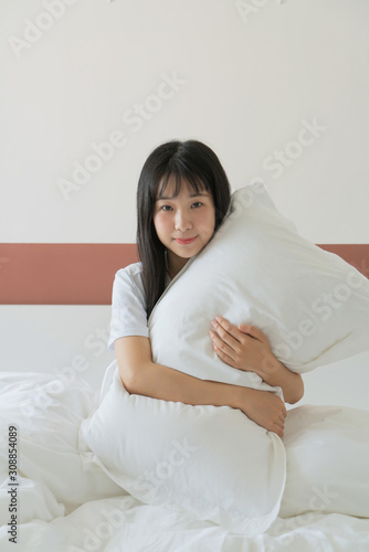 young woman holding pillow on the bed at home © xxxstudio