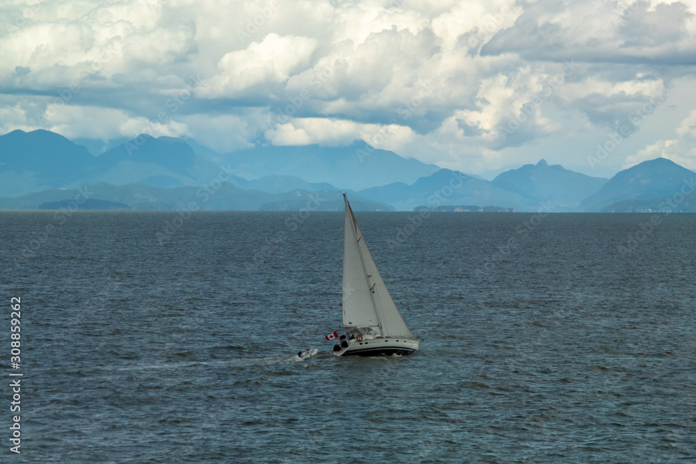 Fototapeta premium Solitude - sailboat at sea, mountains and clouds