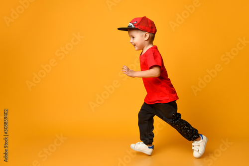 smiling Little boy running left over yellow background