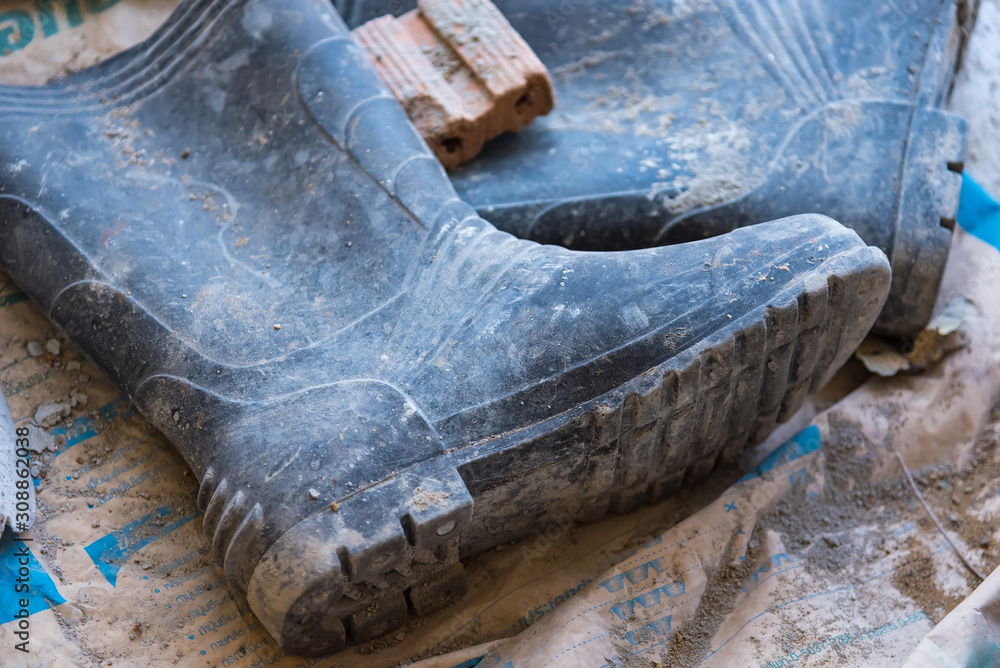 Dirty rubber boots of workers in the construction site. Stock