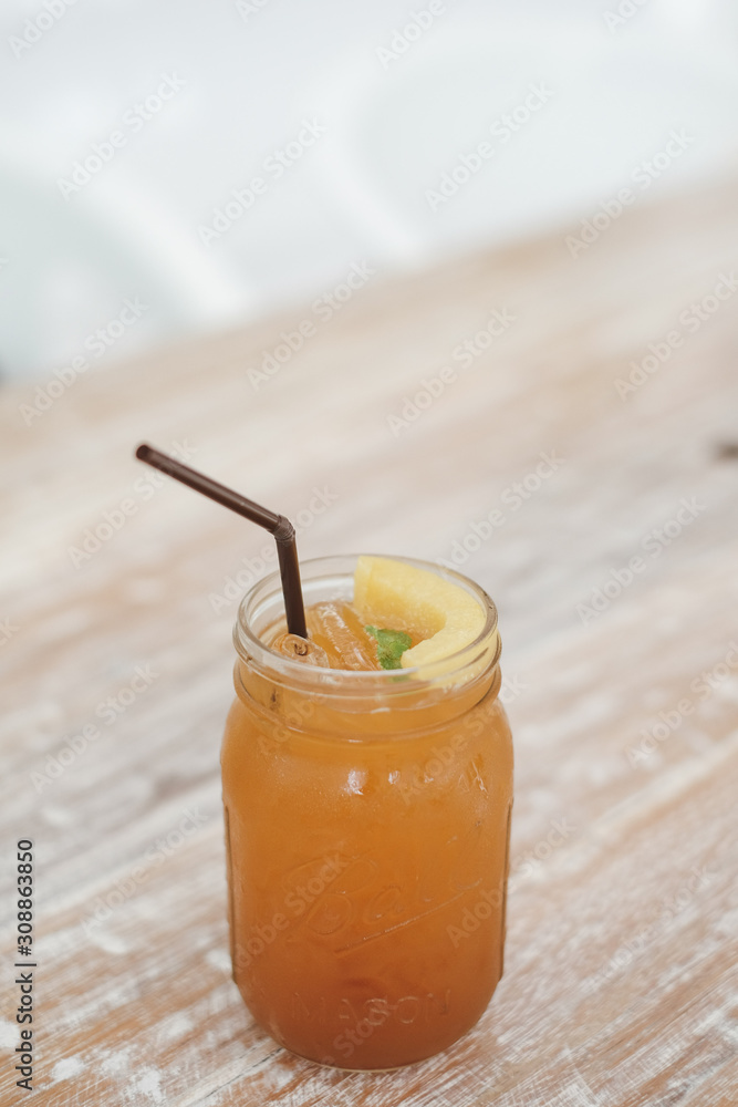 Fresh homemade peach iced tea with mint on a wooden table