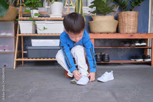 Cuadro en lienzo Asian 3 years old toddler kindergarten kid sitting near shoe rack near front doo