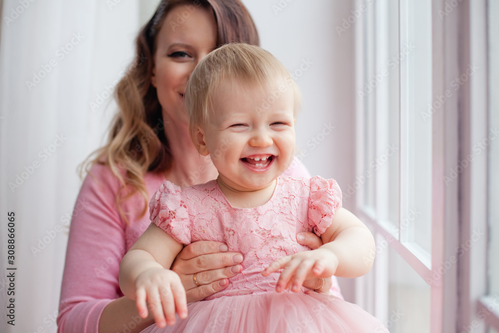 little girl in pink dress with mom on window