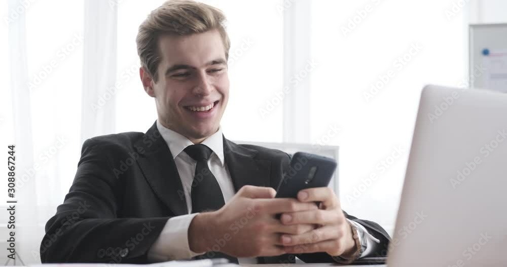 Happy businessman text messaging on mobile phone and taking selfie at office Happy businessman text messaging on mobile phone and taking selfie at office