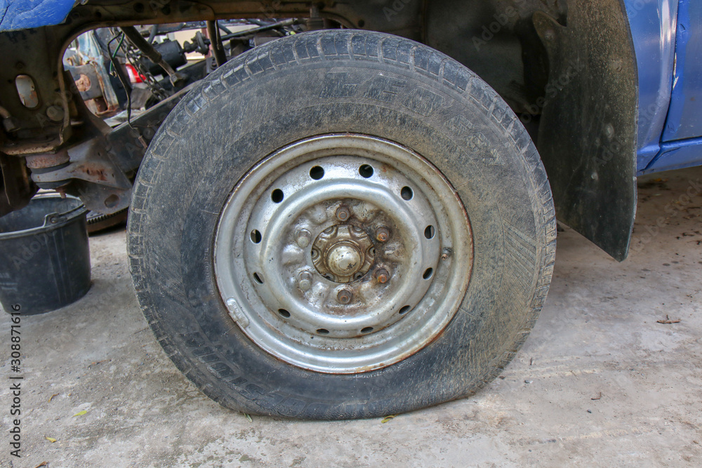 Close up Flat tire and old car on the road waiting for repair.