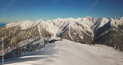 Actionsportlers were dropped by a helicopter at the top of the mountains. The sun is shining brightly in the blue sky. There is a mountain range in the background covered in snow. Drone shooting. photo