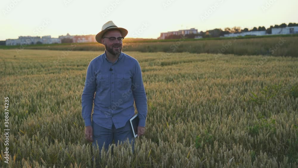 The farmer talking something to somebody at camera in a field The farmer talking something to somebody at camera in a field