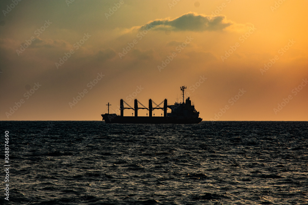 Freight ship silhouette on a sunset horizon