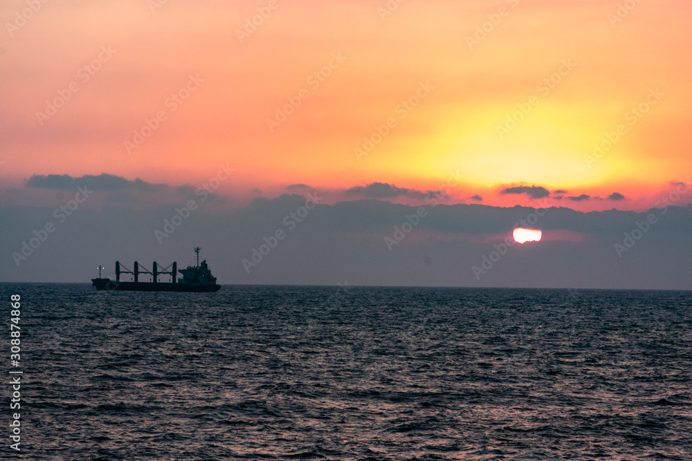 Freight ship silhouette on a sunset horizon Freight ship silhouette on a sunset horizon