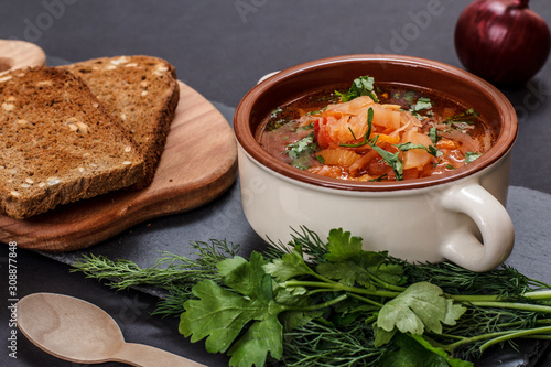 Ukrainian traditional borsch with rye bread on black background.