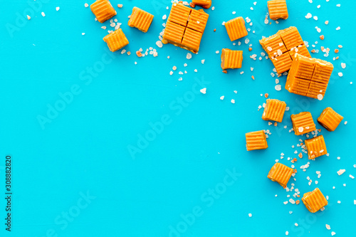 Salted caramel pieces - paradoxical sweets - on blue background top view frame copy space photo