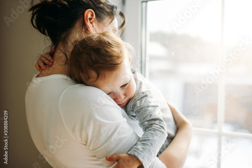 Stampa su tela Young woman mom with baby girl on hands near window at home