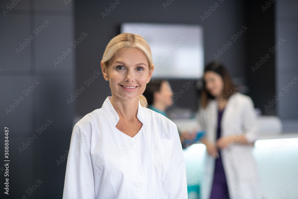 Mature blonde doctor in white robe smiling Mature blonde doctor in white robe smiling