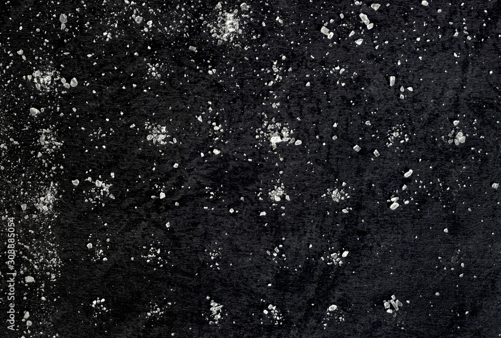 Obraz premium Salt on a background of black texture paper turned out to be a matrix in the manufacture of cookies. Abstraction of the starry sky.