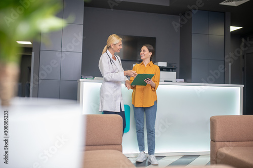 Blond doctor helping in white robe talking to patient photo