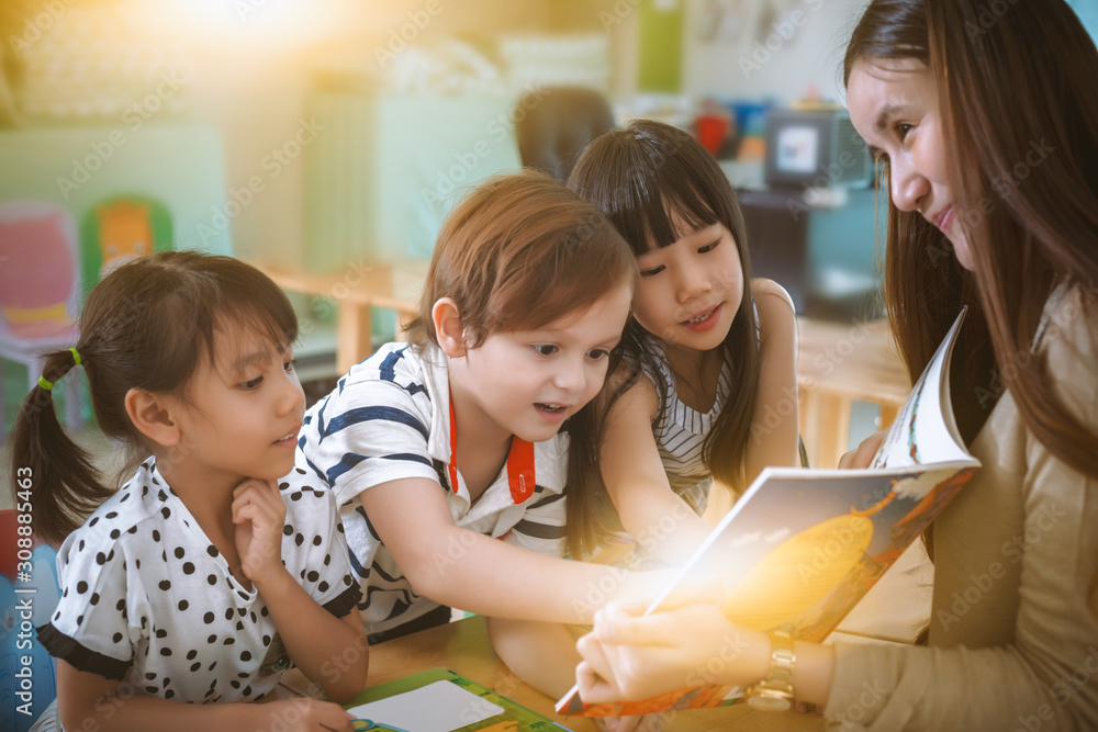 Group children reading book in classroom. Children reading a book with
