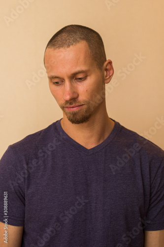 Portrait of a brooding young man in a blue or purple photoball against a beige wall