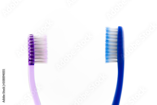 Pair of pink and blue toothbrushes in glass at bathroom isolated over white background.