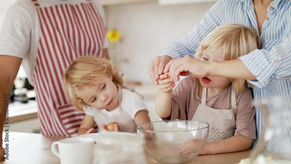 Young family with two small children indoors in kitchen, cooking. Young family with two small children indoors in kitchen, cooking.