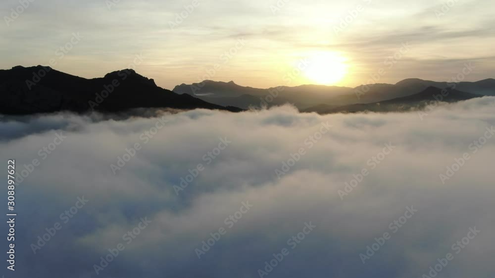 movement between dense fog and clear sky with the sun and mountain peaks movement between dense fog and clear sky with the sun and mountain peaks