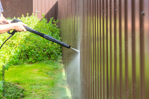 Bild auf Leinwand Cleaning fence with high pressure power washer, cleaning dirty wall