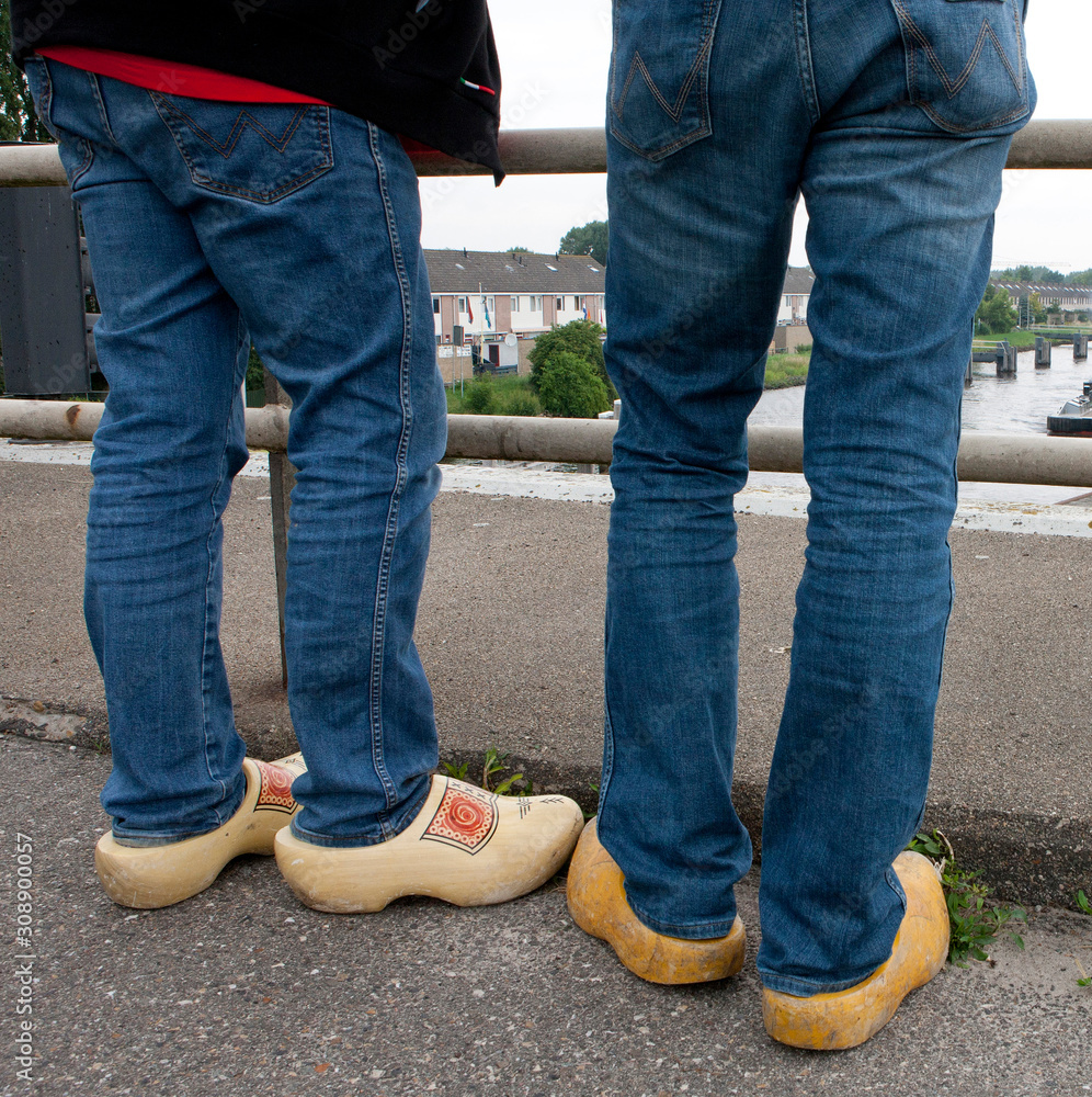 Men watching wearing wooden shoes. Dutch. Transport of a superyacht on a pontoon on the river. Yachting. Shipyard. Shipbuilding. Superyacht.