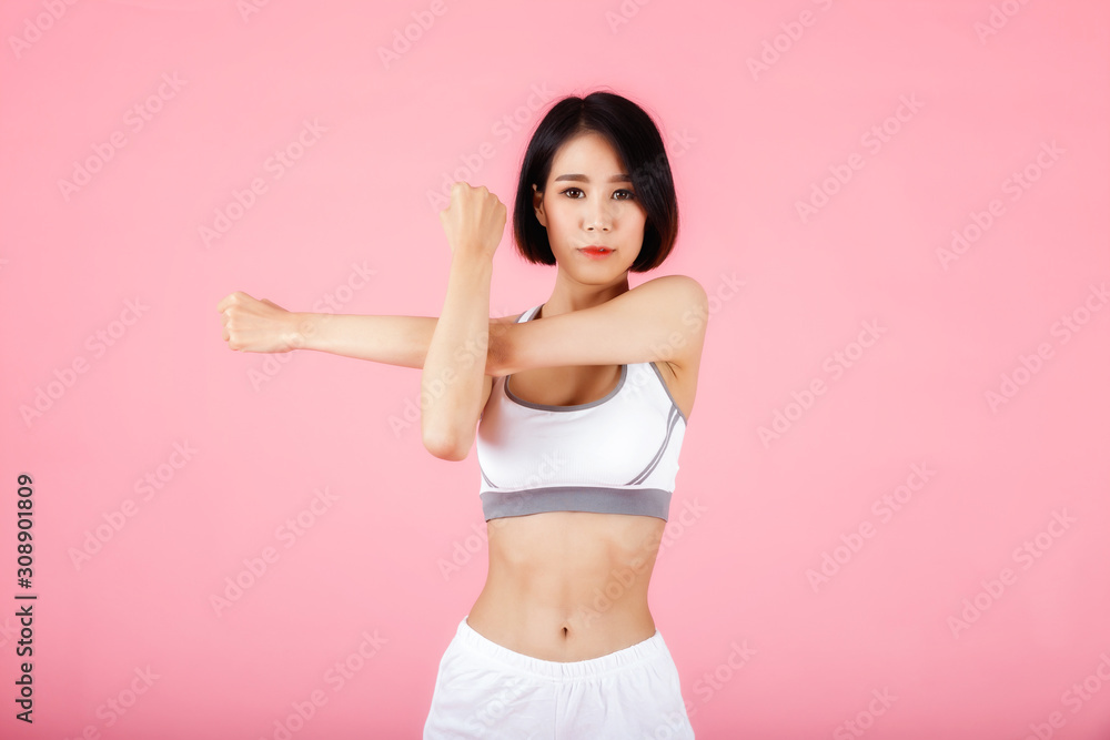 Young sporty woman doing shoulder and arm stretching isolated on pink background. Young sporty woman doing shoulder and arm stretching isolated on pink background.