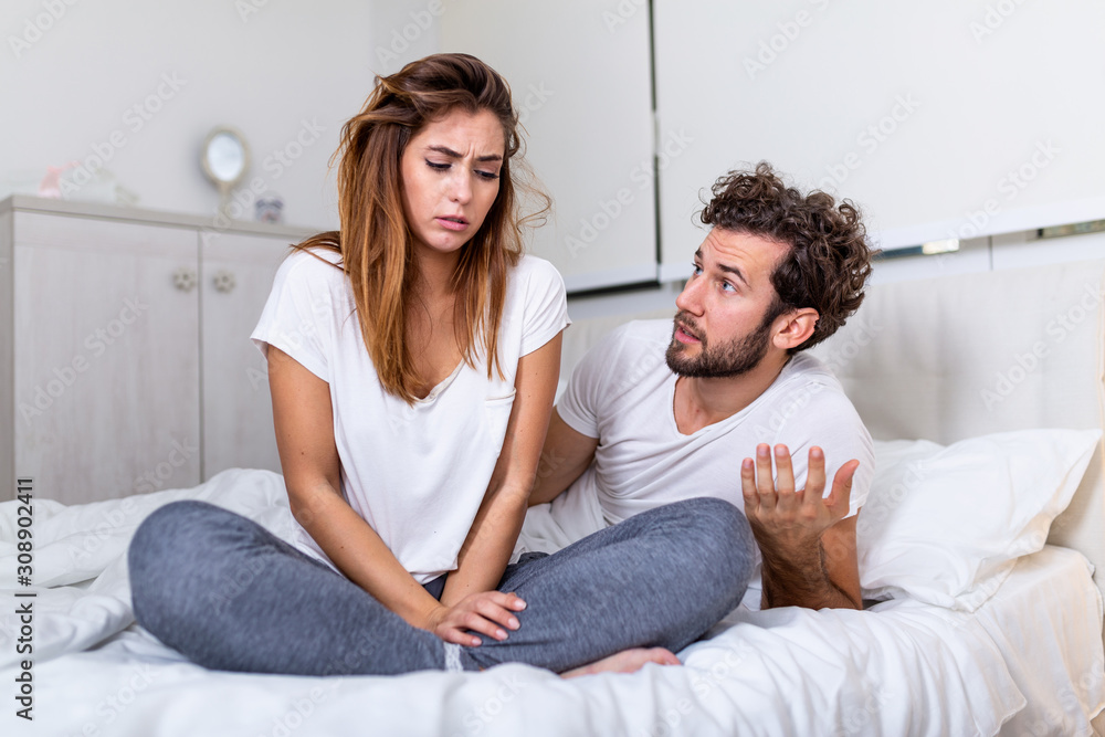 Obraz premium Frustrated sad girlfriend sit on bed think of relationship problems, thoughtful couple after quarrel lost in thoughts, upset lovers consider break up, offended person disappointed by boyfriend