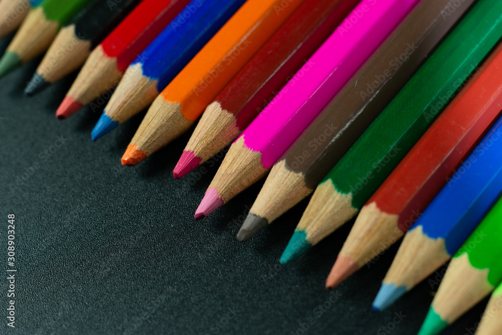 GROUP OF COLORED PENCILS ALIGNED ON BLACK BLACKGROUND GROUP OF COLORED PENCILS ALIGNED ON BLACK BLACKGROUND