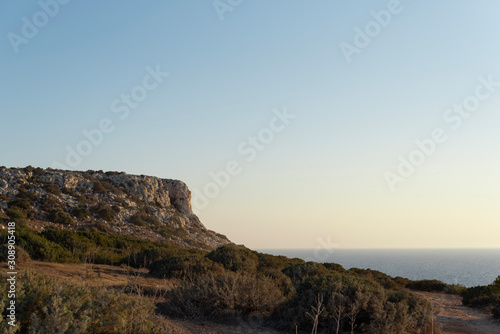 Pacification lonely sunrise. Sunset over the sea, cliffs and hills. 