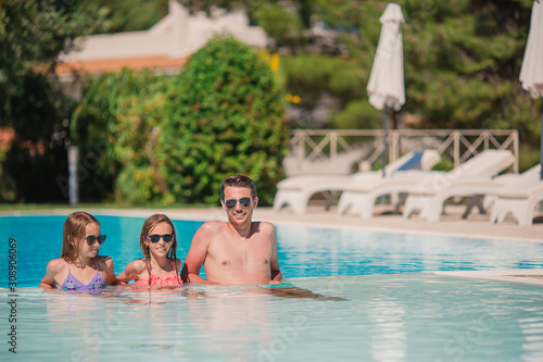 Happy family of three in outdoors swimming pool