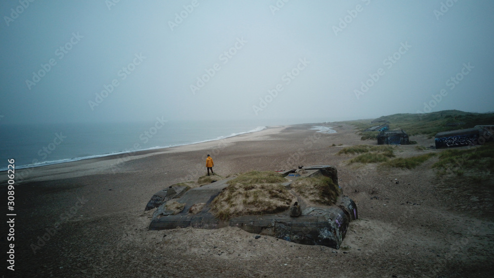 Man in yellow jacket watching beach scenery from bunker