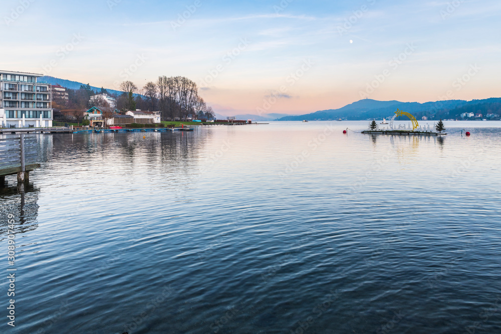 Last lights of the sunset in Velden. Reflections on the water and Christmas atmosphere. Austria.