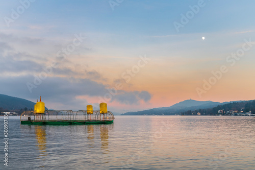 Last lights of the sunset in Velden. Reflections on the water and Christmas atmosphere. Austria.