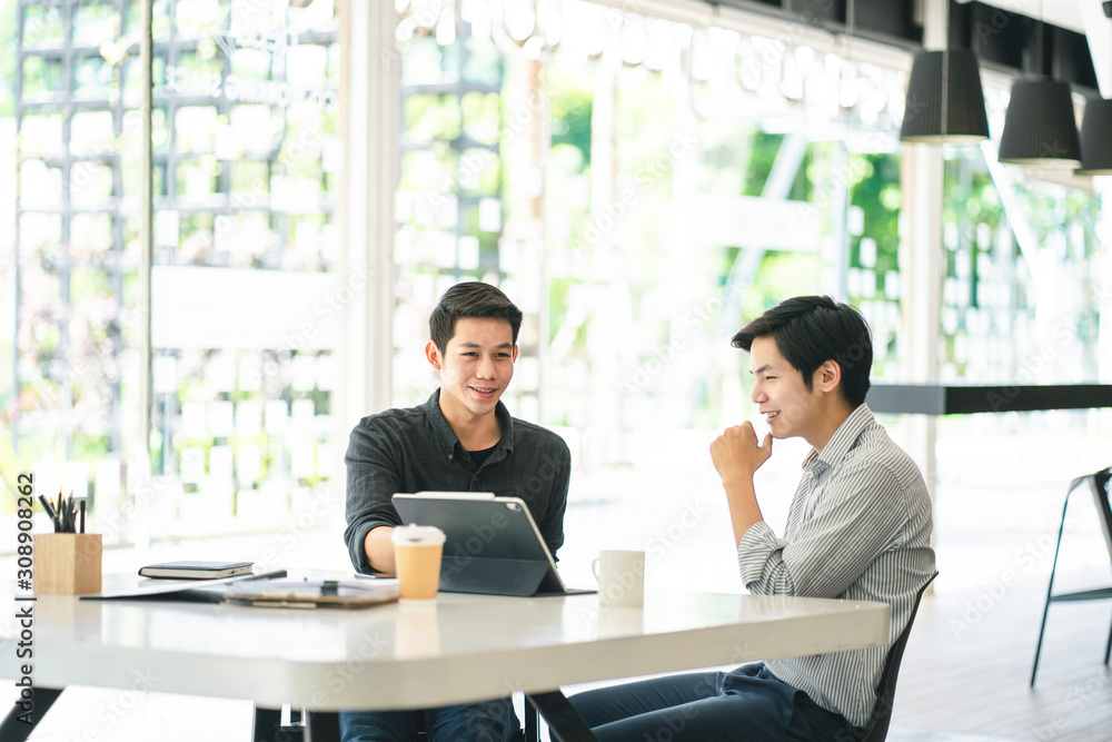 Young Asian businessmen using a digital tablet to discuss information in a modern business working space. Young Asian businessmen using a digital tablet to discuss information in a modern business working space.