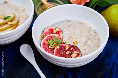 A bowl of porridge with figs slices and walnuts  on dark blue background.