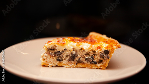 A piece of pie with meat and mushrooms lies on a plate