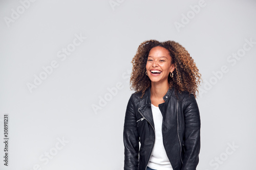 Waist Up Studio Shot Of Happy Young Woman Wearing Leather Jacket Laughing Off Camera photo