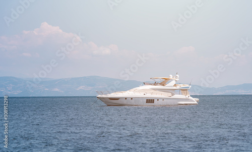 Luxury white yacht on horizon at the sea with island sillhouette at background