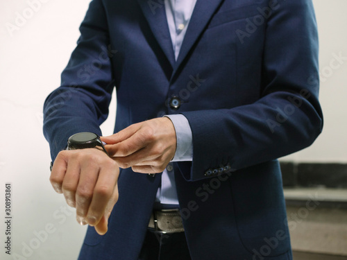 Man in blue blazer jacket with watch walking down stairs while fixing sleeve